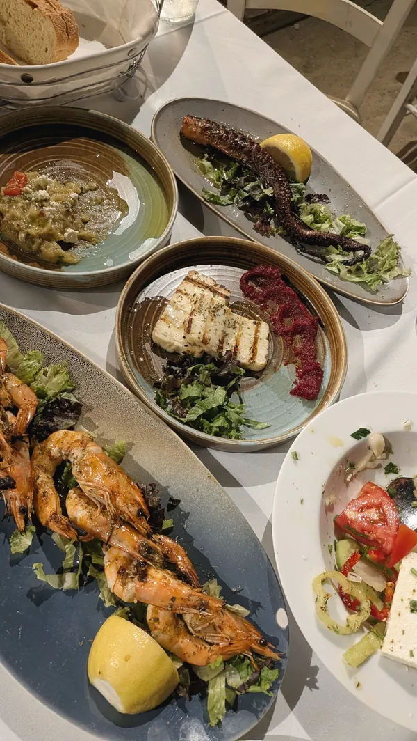 Grilled octopus, prawns, halloumi and a Greek salad on a taverna table