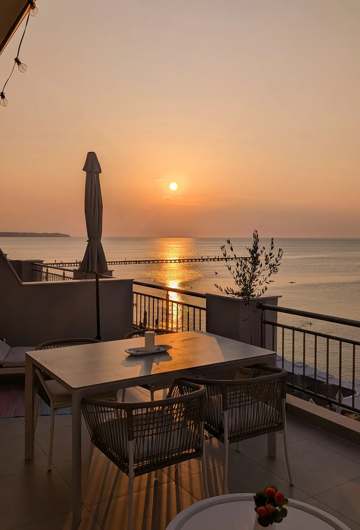 The sun setting over the sea and the pier in Perea, seen from the terrace