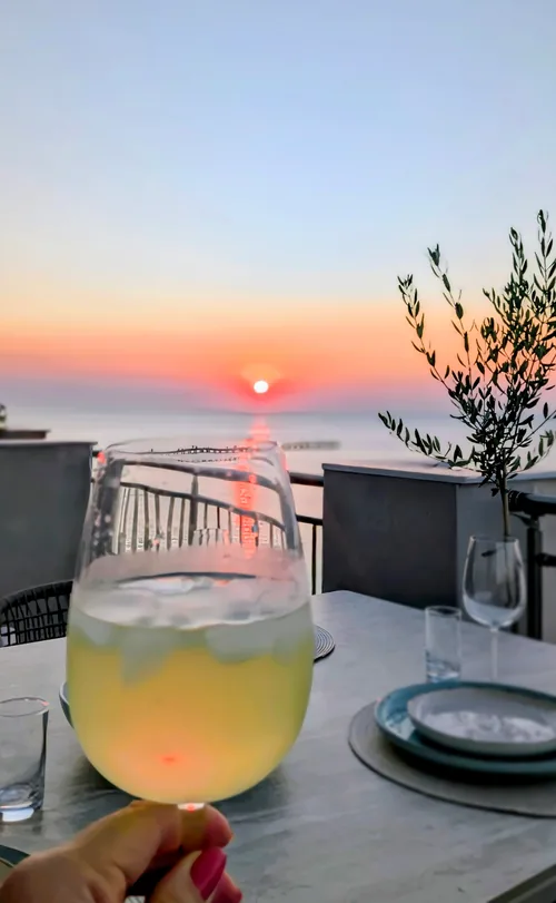 A glass of limoncello on the terrace table as the sun sets over the sea