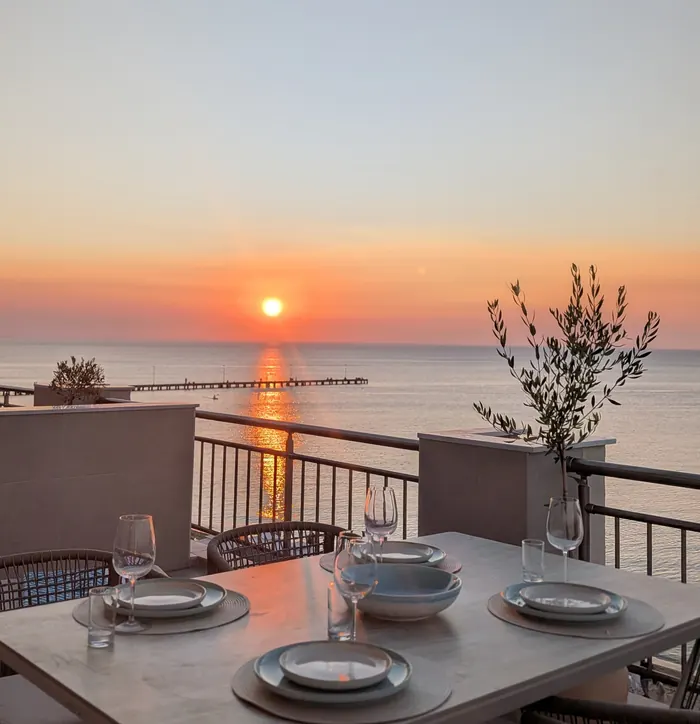 Table set for dinner on the terrace as the sun sets over the sea