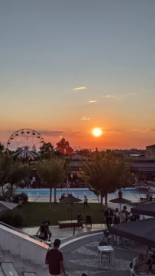 Sunset over Thessaloniki with a ferris wheel and palm trees